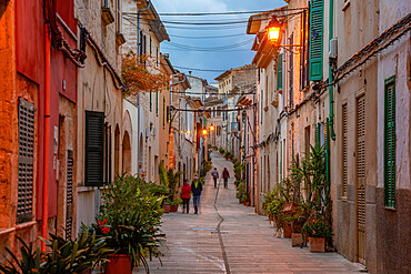 People in street in narrow street at dusk in the old town of Alcudia, Alcudia, Majorca, Balearic Islands, Spain, Mediterranean, Europe