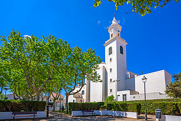 View of whitewashed Catholic Church framed by trees against blue sky, Sant Lluis, Menorca, Balearic Islands, Spain, Mediterranean, Europe