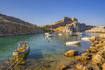 View of sailboats in St Paul's Bay, Lindos and Lindos Acropolis from beach, Lindos, Rhodes, Dodecanese Island Group, Greek Islands, Greece, Europe