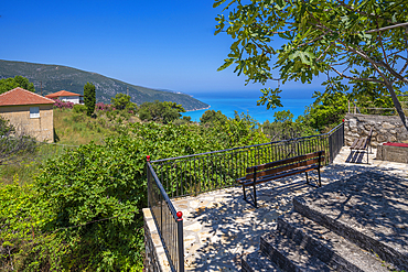 View of seat overlooking coastline, sea and hills near Agkonas, Kefalonia, Ionian Islands, Greek Islands, Greece, Europe