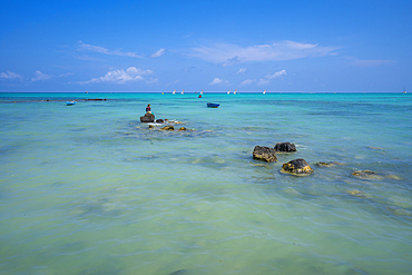 View of man fishing from Mont Choisy Beach and turquoise Indian Ocean on sunny day, Mauritius, Indian Ocean, Africa