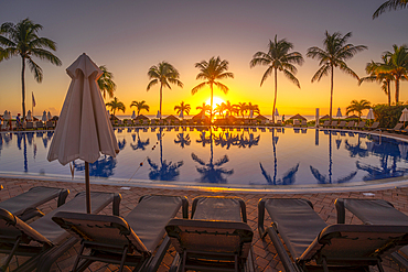 View of sunrise and palm tree reflections in hotel pool near Puerto Morelos, Caribbean Coast, Yucatan Peninsula, Mexico, North America