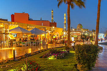 View of cafe and restaurant in Hurghada Marina and Al Mina Mosque in background at dusk, Hurghada, Red Sea Governorate, Egypt, North Africa, Africa