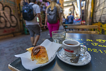 View of couple walking past expresso coffee on cafe table on bustling Via San Biagio Dei Librai, Naples, Campania, Italy, Europe