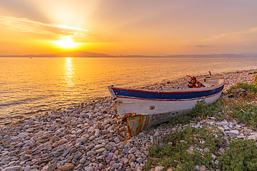 View of boat on pebble beach near Skala Kallirachis at sunset, Skala Kallirachis, Thassos, Aegean Sea, Greek Islands, Greece, Europe