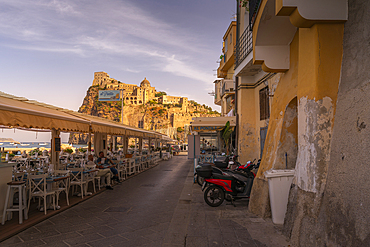 View of restaurants and Aragonese Castle at sunset, Port of Ischia, Island of Ischia, Campania, Italy, Europe