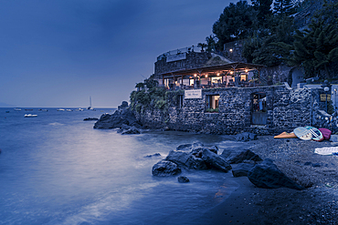 View of coastline restaurant near Aragonese Castle at dusk, Port of Ischia, Island of Ischia, Campania, Italy, Europe