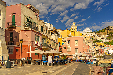 View of restaurant in Marina di Corricella and Church of Santa Maria delle Grazie in background, Procida, Phlegraean Islands, Gulf of Naples, Campania, Southern Italy, Italy, Europe