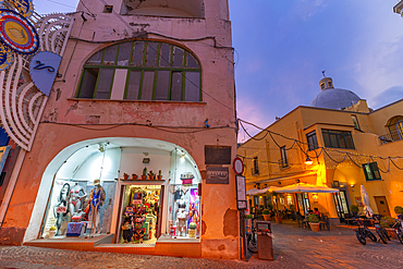 View of shops on Via Vittorio Emanuele in the fishing port at dusk, Procida, Phlegraean Islands, Gulf of Naples, Campania, Southern Italy, Italy, Europe