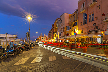 View of shops and Church Madonna delle Grazie in the fishing port Marina Grande with trail lights at dusk, Procida, Phlegraean Islands, Gulf of Naples, Campania, Southern Italy, Italy, Europe