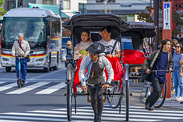 View of Japanese rickshaw or jinrikisha in busy street scene, Asakusa, Taito City, Tokyo, Japan, Asia