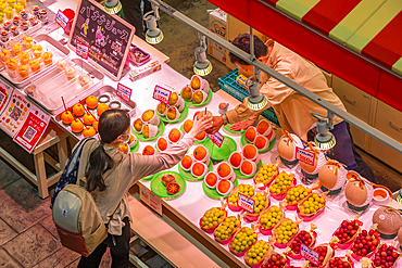 Elevated view of customer being served at colourful fresh fruit stall in Omicho Market, Kanazawa City, Ishikawa Prefecture, Honshu, Japan