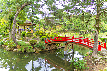 View of red footbridge over Takueichi Pond in Shukkeien Garden, Kaminoboricho, Naka Ward, Hiroshima, Honshu, Japan