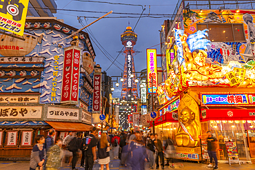 View of Tsutenkaku Tower and restaurants neon lights at dusk in the Shinsekai area, Osaka, Honshu, Japan