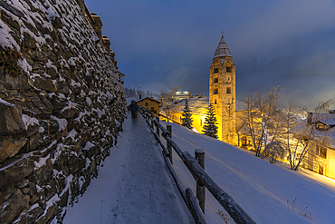 View of Church of Saint Pantalon and the snow covered town centre and mountainous background in winter at dusk, Courmayeur, Aosta Valley, Italy, Europe