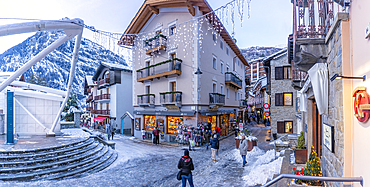 View of shops, town centre and snow covered mountains in Courmayeur at dusk during Christmas, Courmayeur, Aosta Valley, Italy, Europe