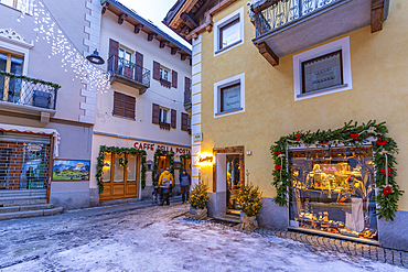 View of shops, town centre and snow covered mountains in Courmayeur at dusk during Christmas, Courmayeur, Aosta Valley, Italy, Europe