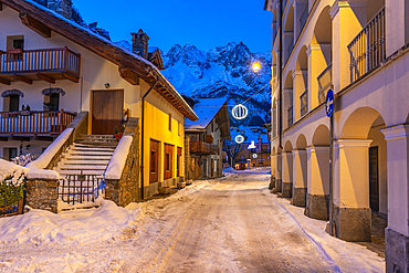 View of town centre and snow covered mountains in background at dusk, Courmayeur, Aosta Valley, Italy, Europe