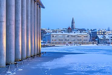 View of the Iceland model building and Hallgrimskirkja Church of Reykjavík from Tjörnin lake at dusk during winter, Reykjavík, Iceland, Europe