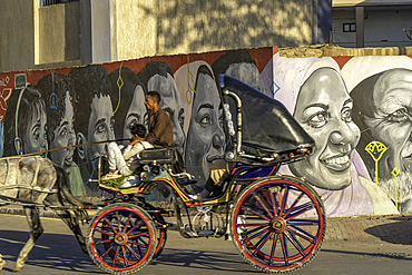 View of carriage and painted faces on wall on the Nile Corniche on a sunny day, Aswan, Nubia, Egypt, Africa