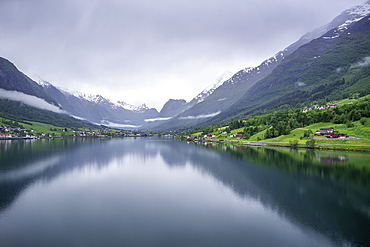 View of Olden village and mountains reflecting in Nordfjorden during summer, Norway, Scandinavia, Europe