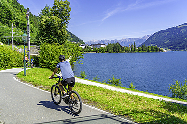 View of cyclist by Lake Zell in Zell am See on a sunny day, Zell am See, Salzburg, Austria, Europe