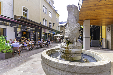 View of water fountain and restaurants in Zell am See on a sunny day, Zell am See, Salzburg, Austria, Europe