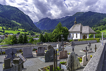 View of chapel and graveyard with mountains in background on a sunny day, Kaprun, Salzburg, Austria, Europe