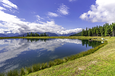 View of reflection of mountains and clouds in Plettsaukopf Reservoir on a sunny day, Bruckberg, Salzburg, Austria, Europe