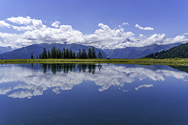 View of reflection of mountains and clouds in Plettsaukopf Reservoir on a sunny day, Bruckberg, Salzburg, Austria, Europe