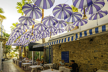 View of umbrellas at taverna in Limenas Chersonisou, Crete, Greek Islands, Greece, Europe