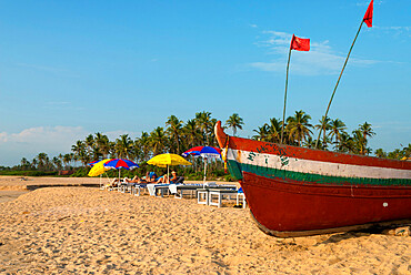 Traditional fishing boat and sunbathers on beach, Benaulim, Goa, India, Asia