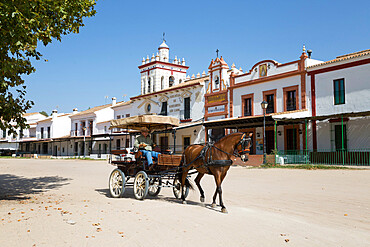 Horse and carriage riding along sand streets with brotherhood houses behind, El Rocio, Huelva Province, Andalucia, Spain, Europe