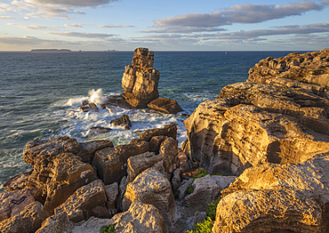 Waves crashing against rock stack at Cabo Carvoeiro in evening sunlight with Ilha da Berlenga in the distance, Peniche, Centro Region, Estremadura, Portugal, Europe