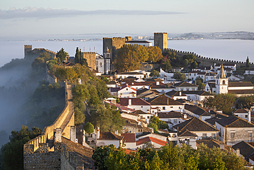 View over the old town and walls of Obidos in morning mist, Obidos, Centro Region, Estremadura, Portugal, Europe