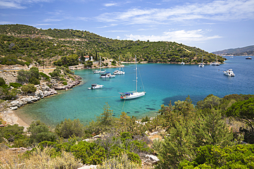 Yachts anchored in rocky cove with crystal clear turquoise water at Russian Bay, Poros, Saronic islands, Greek Islands, Greece, Europe