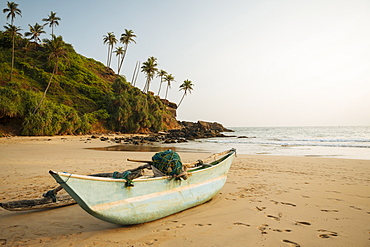 Traditional wooden boat on Talalla Beach at dusk, South Coast, Sri Lanka, Asia