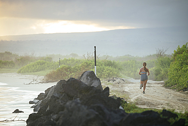 Woman running alongside beach, Isla Isabela, Galapagos Islands, Ecuador
