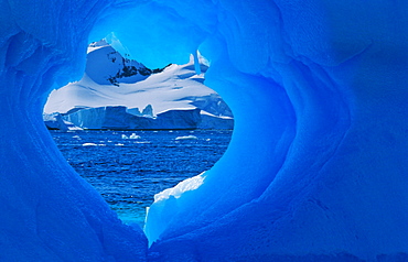 Heartshaped hole in an Antarctic blue iceberg. PlÃ©neau Island, Antarctica