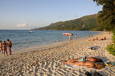 People walking along Beau Vallon beach, early evening light, Mahe, Seychelles, Indian Ocean