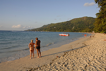 People walking along Beau Vallon beach, early evening light, Mahe, Seychelles, Indian Ocean