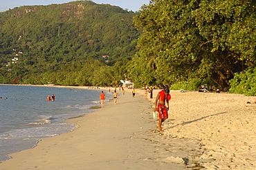 People walking along Beau Vallon beach, early evening light, Mahe, Seychelles, Indian Ocean