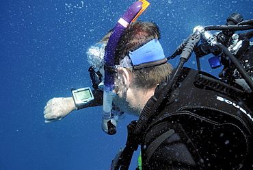 Scuba diver checking computer during safety or decompression  stop, Mahe, Seychelles, Indian Ocean