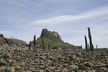 Holy Island or Lindisfarne Castle (view from shore with posts from old ruined pier), Holy Island, Northumberland, UK.