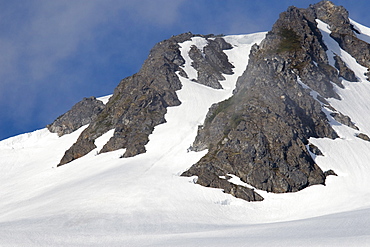 View of the snow-covered cliffs in sunlight surrounding Takatz Bay on Baranof Island, Southeast Alaska, USA. Pacific Ocean.