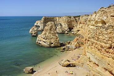 Overview of tourists on beach, sandstone cliffs and seastacks at Praia da Marinha, near Carvoeiro, Algarve, Portugal, Europe