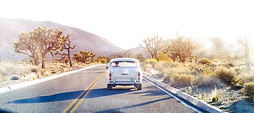 Vintage car driving on desert road