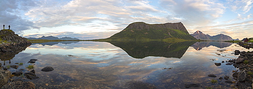 Panorama of pink clouds and peaks reflected in water at night time, Vengeren, Vagspollen, Lofoten Islands, Norway, Scandinavia, Europe