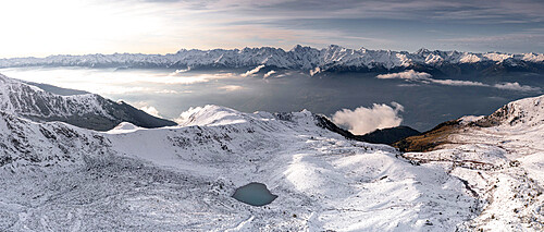 Aerial view of snowcapped Orobie Alps and Piani di Rhon emerging from autumn fog at dawn, Rhaetian Alps, Lombardy, Italy, Europe