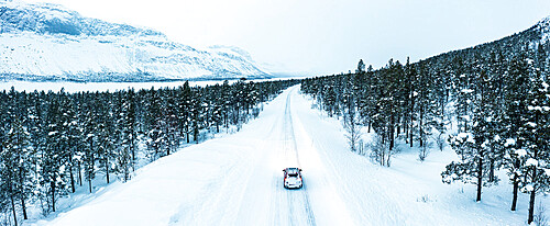 Overhead car-view driving on icy road crossing a forest covered with snow, Stora Sjofallet, Norrbotten County, Lapland, Sweden, Scandinavia, Europe